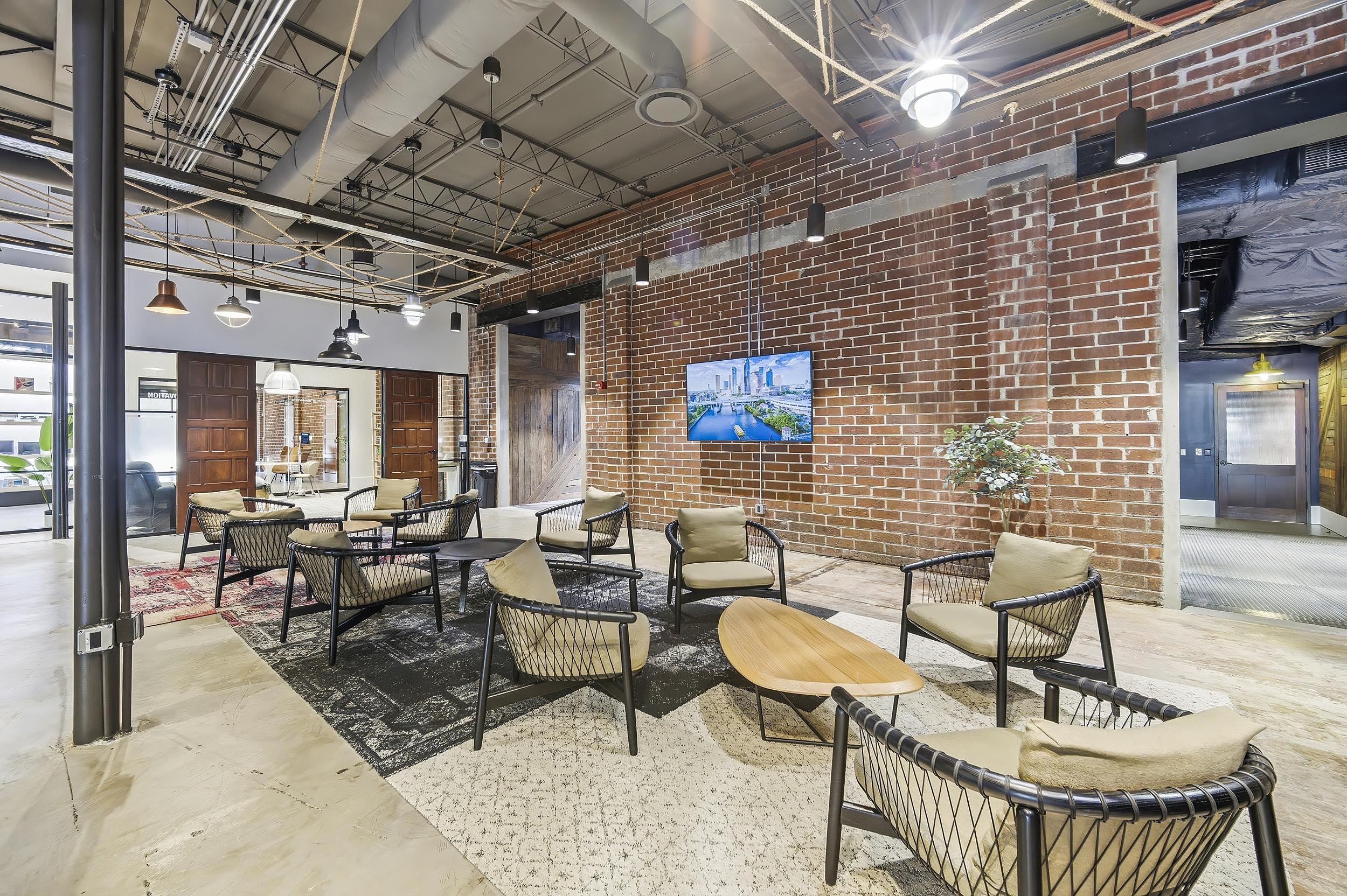 Industrial lounge with brick walls, modern lounge seating, and wall-mounted display.