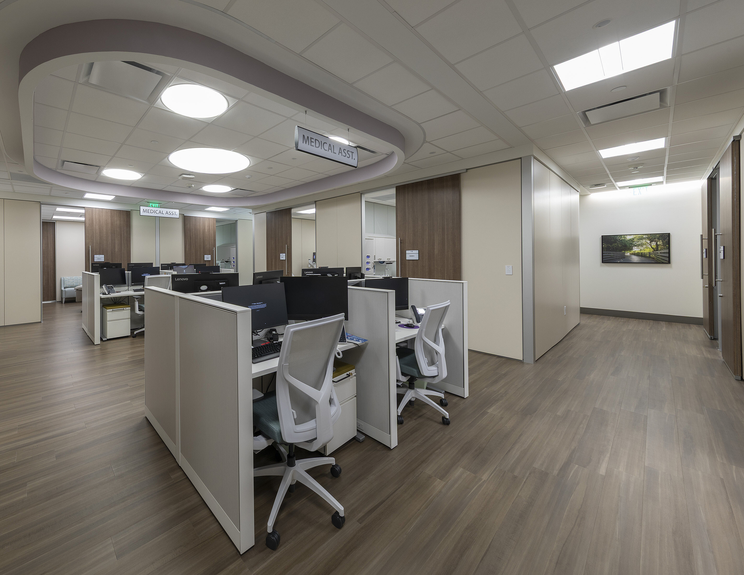 Medical office break area with long counter, coffee station, wood floors, and table with chairs.