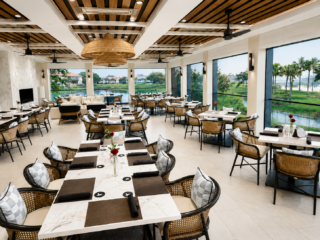 Upscale dining room with lake views, woven chairs, and wood-accented ceiling.