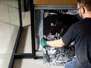 Person removing a panel to reveal recycled material insulation inside a wall system.