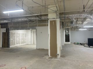 Unfinished commercial office interior with exposed utilities, partially finished walls and open floor space.