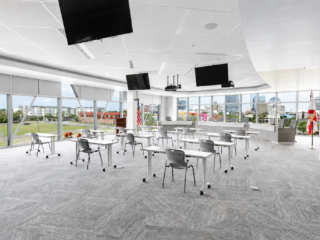 Training room with spaced tables, monitors, and panoramic city views through glass walls.