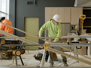 Construction workers cutting wood planks with power saws inside a building under renovation.