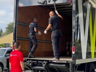 Delivery crew loading items into a Workscapes box truck with a liftgate.