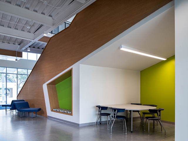 Modern interior collaboration area with study tables, seating, and wood-accented staircase.
