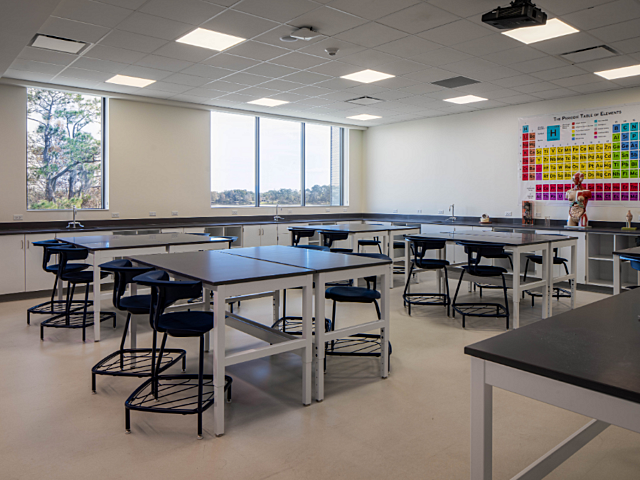 Science classroom with lab tables, stools, sinks, and a periodic table display.
