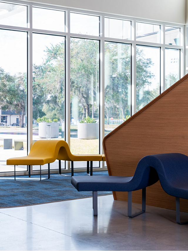 Lobby seating area with sculptural benches, wood partition, and floor-to-ceiling windows.